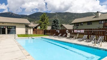 Ein Swimmingpool mit Liegestühlen, einem Holzzaun und einem Berg im Hintergrund.