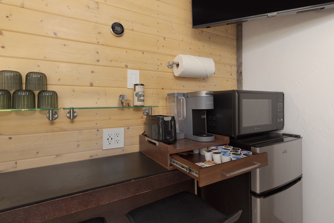 A kitchenette with a coffee maker, microwave, and a refrigerator.