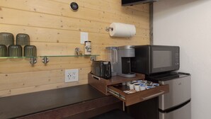 Uma cozinha compacta com cafeteira, micro-ondas e geladeira.