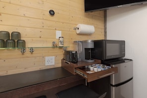 Une petite cuisine équipée d’une machine à café, d’un four à micro-ondes et d’un réfrigérateur.