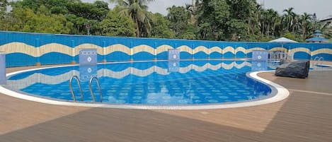 Una piscina con un diseño ondulado azul y beige en las paredes, rodeada por una terraza de madera.