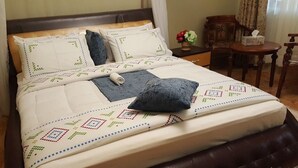 A neatly made bed with a patterned bedspread, pillows, and a rolled-up blanket. - Cactus Hill Side Hotel (Gulu)