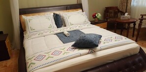 Un lit bien fait, avec une couvre-lit à motifs, des oreillers et une couverture enroulée.