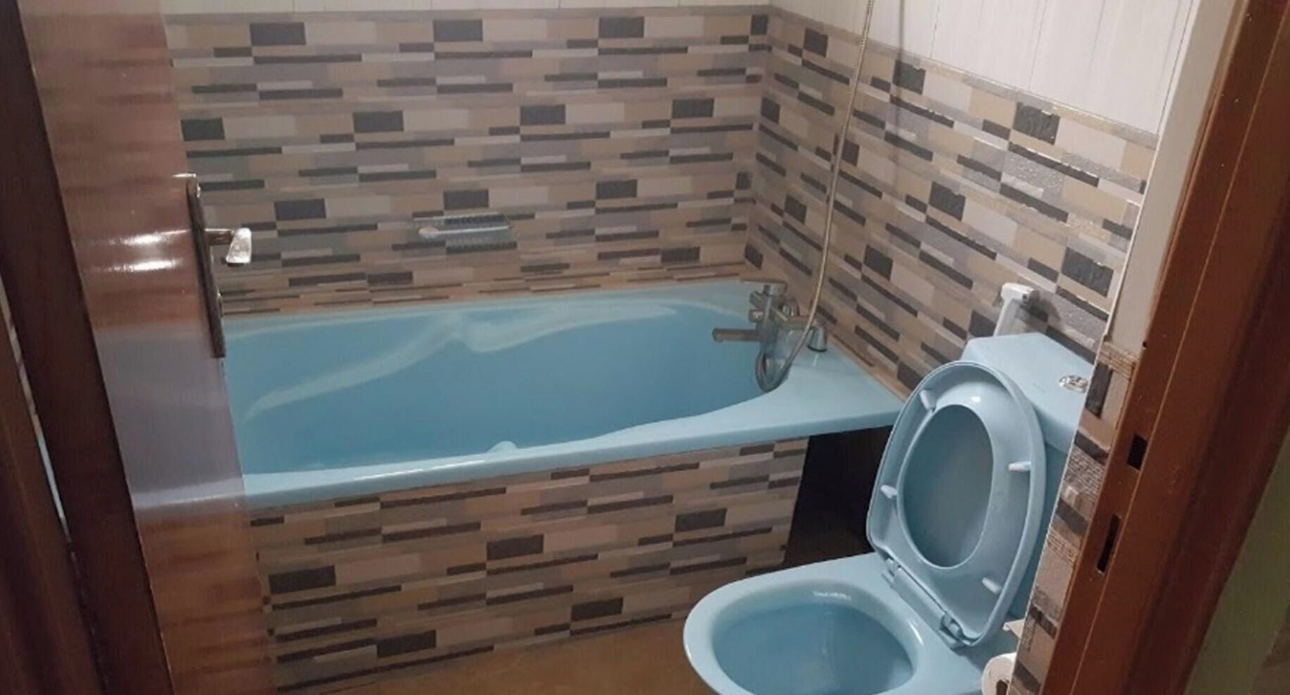 A bathroom with a bathtub, toilet, and tiled walls.
