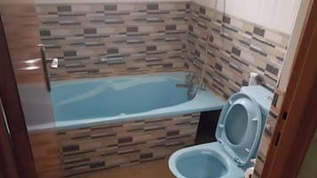 A bathroom with a bathtub, toilet, and tiled walls.