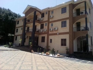 A multi-story building with balconies, air conditioning units, and a paved entrance area. - Cactus Hill Side Hotel (Gulu)