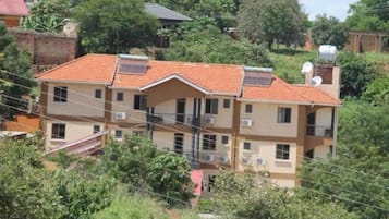 A multi-story residential building with a tiled roof, multiple balconies, and a satellite dish.