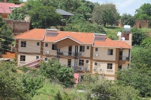 A multi-story residential building with a tiled roof, multiple balconies, and a satellite dish. - Cactus Hill Side Hotel (Gulu)