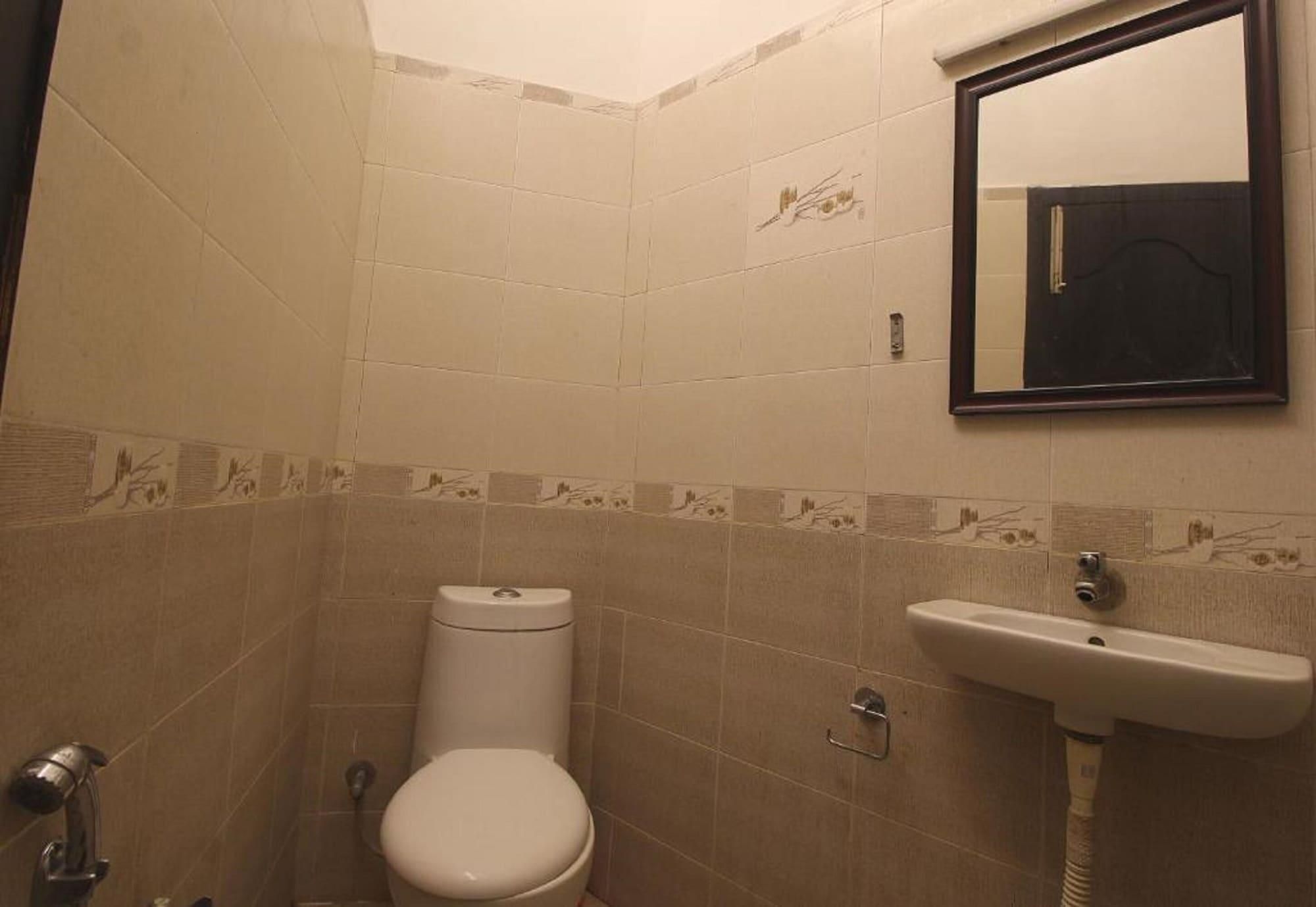 A bathroom with a toilet, sink, and a mirror.