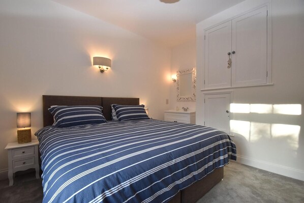 Un dormitorio con cama, mesitas de noche, un espejo y un armario.