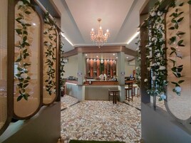 Zona de bar con un cantinero, suelo de baldosas y plantas decorativas.