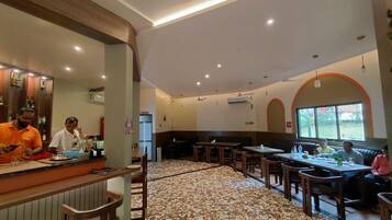 A restaurant with a bar area, seating arrangements, and a patterned floor.
