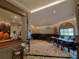 Un restaurante con zona de bar, disposición de mesas y suelo estampado.