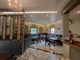 Interior de un restaurante con suelo de mosaico, distribución de mesas y una araña.