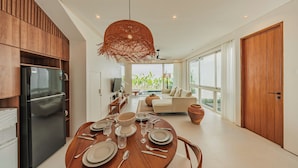 Una cocina moderna con comedor, muebles de madera, un refrigerador negro y una mesa de comedor lista para cuatro comensales.
