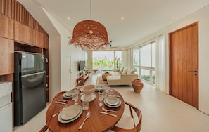 A modern kitchen with a dining area, wooden cabinetry, a black refrigerator, and a dining table set for four. - Villa Binginzie by Betterplace (Bingin)