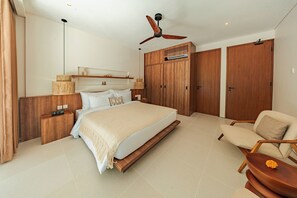 Ein Schlafzimmer mit einem Bett, Nachttischen, einem Sessel, einem Deckenventilator und Holzschränken.