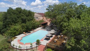 A swimming pool with lounge chairs, a patio area with tables and umbrellas, and a building in the background. - Sedia Riverside Hotel (Maun)