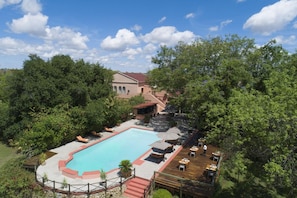A swimming pool with lounge chairs, a patio area with tables and umbrellas, and a building in the background. - Sedia Riverside Hotel (Maun)