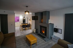 Una sala de estar moderna con chimenea, un comedor y una cocina al fondo.