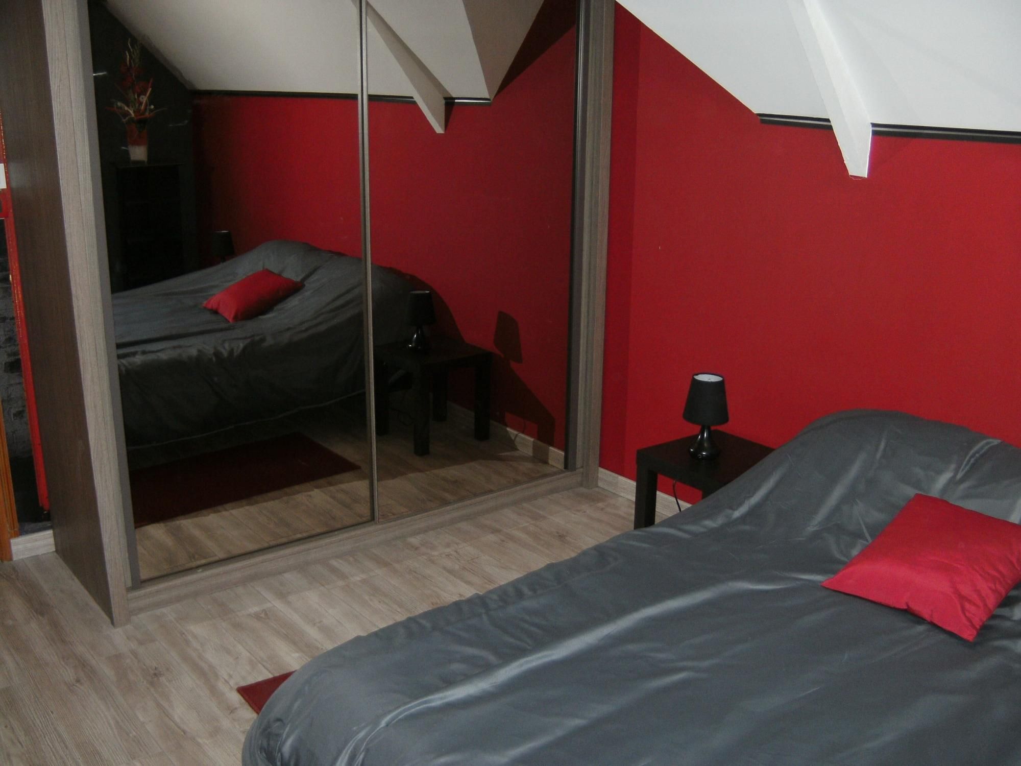 A bedroom with a bed, a nightstand, a lamp, and a mirror.