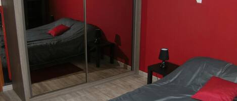Une chambre Ă coucher avec un lit, une table de chevet, une lampe et un miroir.