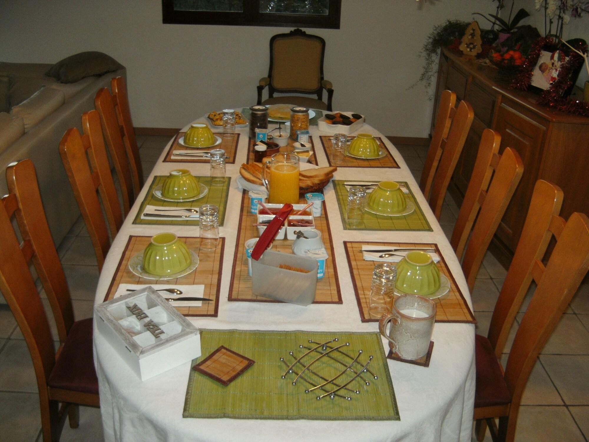 A dining table set for breakfast with multiple plates, cups, and a pitcher of orange juice.