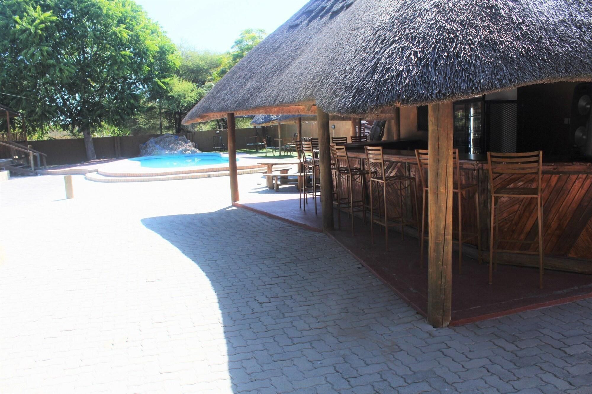 A covered outdoor seating area with a pool in the background.