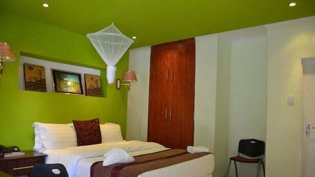 Een hotelkamer met een bed, een stoel, een kledingkast en kunst aan de muur.