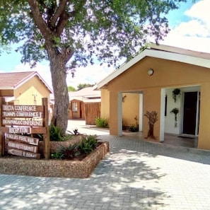 A building with a sign indicating a reception area and a pool bar. - Wingate Hotel Maun (Francistown)