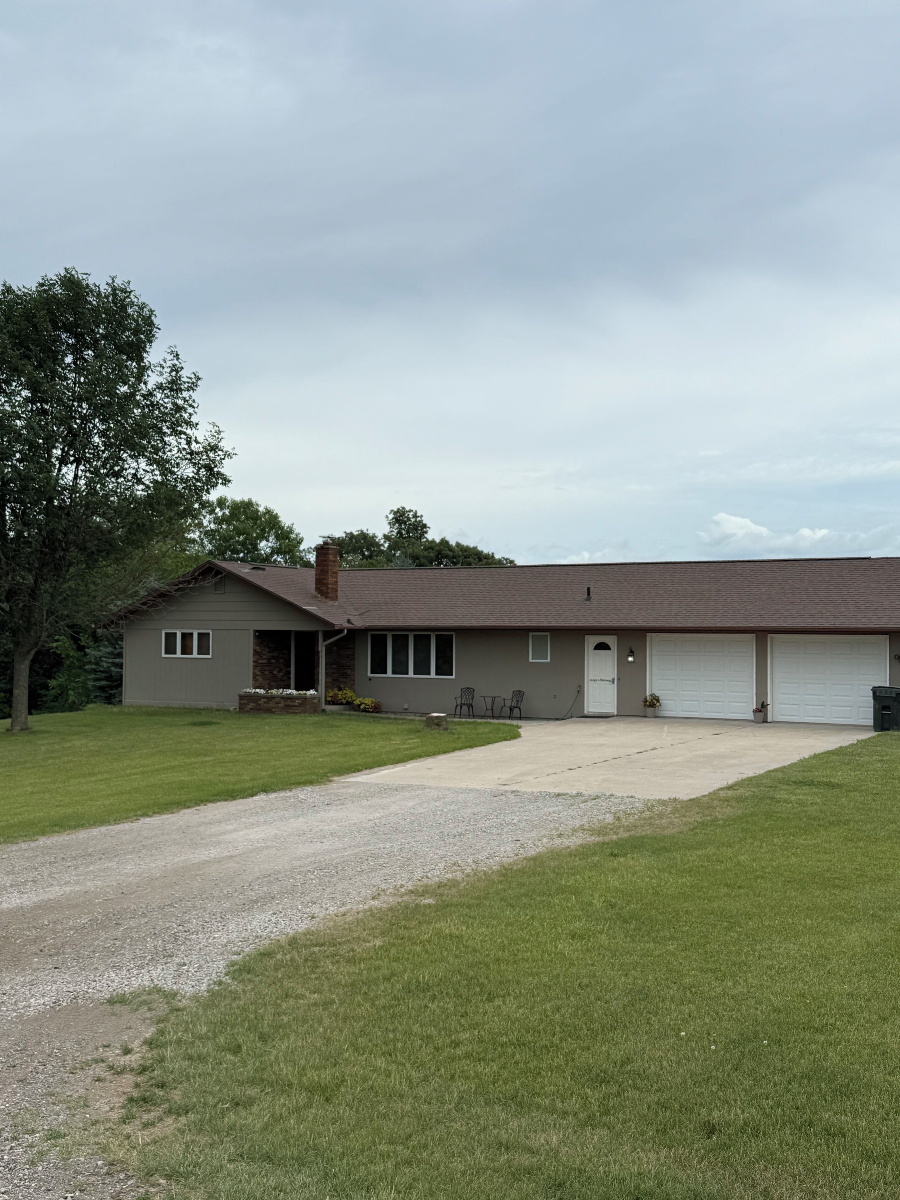 Une maison de plain-pied avec un garage, une pelouse devant et une allée en gravier.
