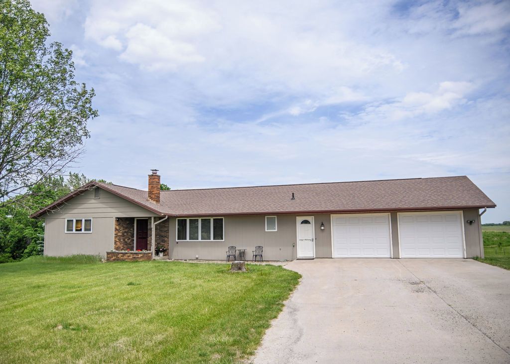 A single-story house with a garage, a front porch with chairs, and a well-maintained lawn.