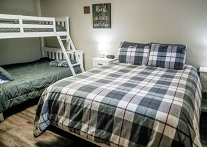 Ein Zimmer mit Etagenbetten, einem Nachttisch mit Lampe und einem motivierenden Spruch an der Wand.