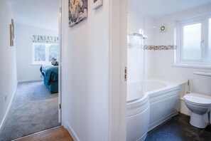 A bathroom with a bathtub, toilet, and a window.