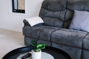 A grey sofa with a white throw blanket and a grey pillow. - The Helensvale Haven | Modern 4BR Family Retreat (Helensvale)