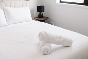 A neatly made bed with a rolled towel on the side. - The Helensvale Haven | Modern 4BR Family Retreat (Helensvale)