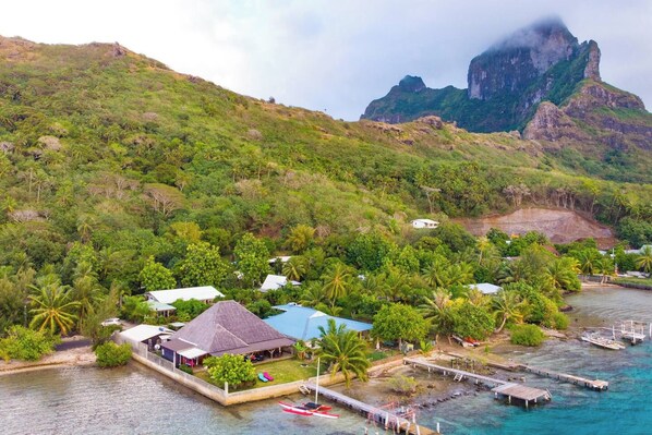 Um resort costeiro com vários edifícios, um cais e montanhas ao fundo.