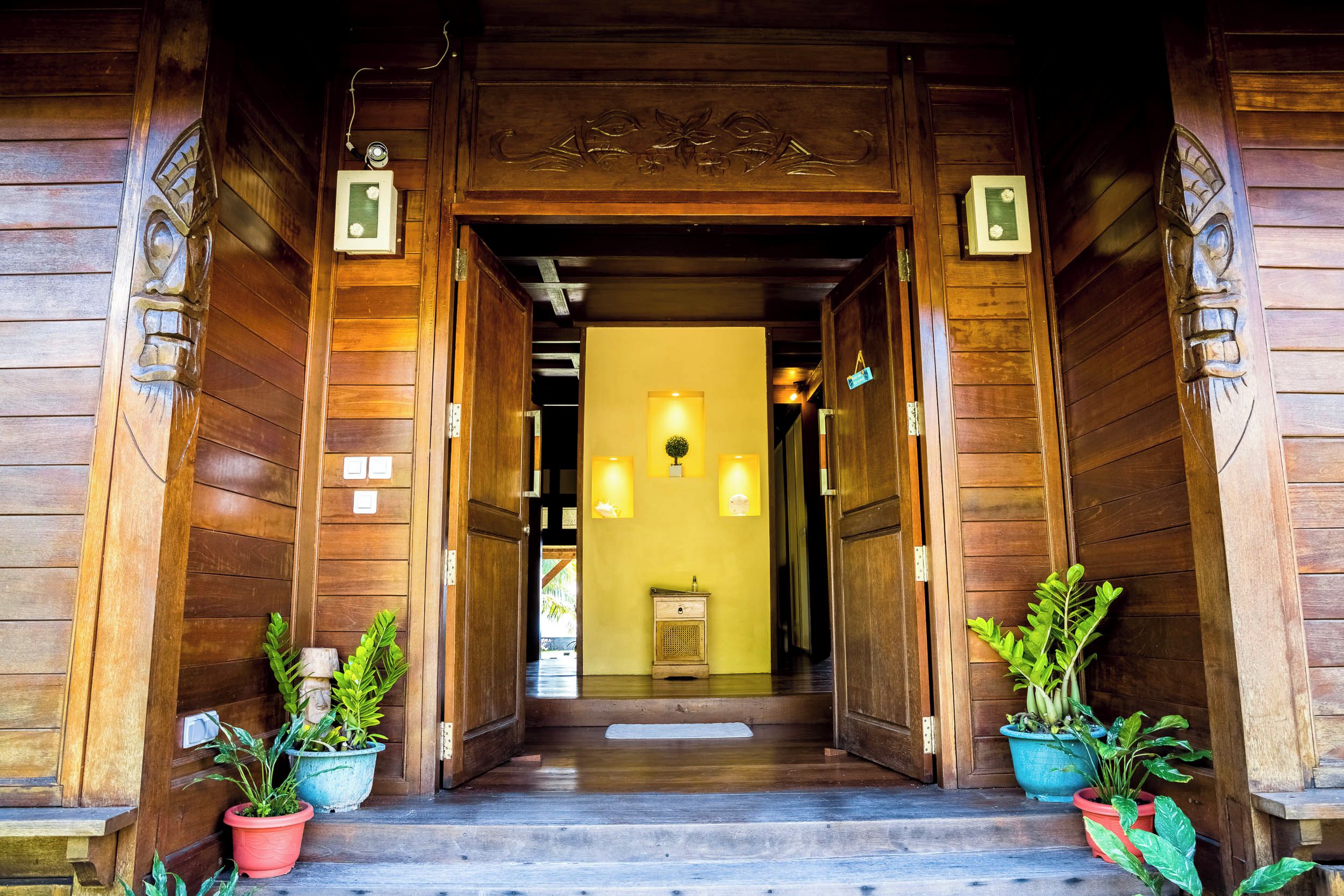 A wooden entrance with a central hallway leading to a room with a light fixture.