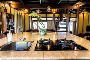 A kitchen with a central island, stainless steel sink, and gas stove. - Bora Bora waterfront sunrise villa (Bora Bora)