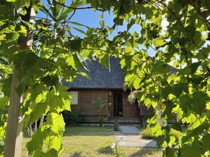 Ein Holzhaus mit geneigtem Dach, einer Veranda und einem gepflegten Rasen.