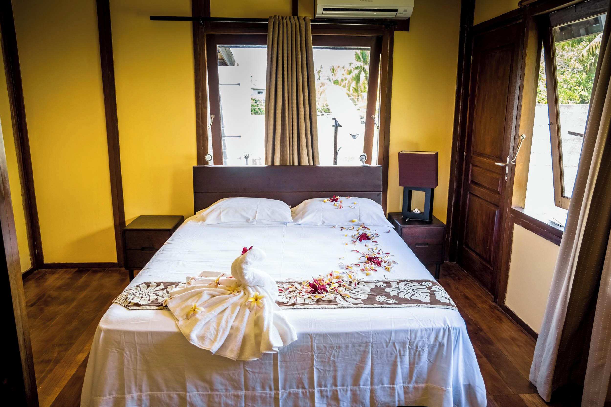 Une chambre d’hôtel avec un lit, une table de chevet, une lampe et une fenêtre avec des rideaux.