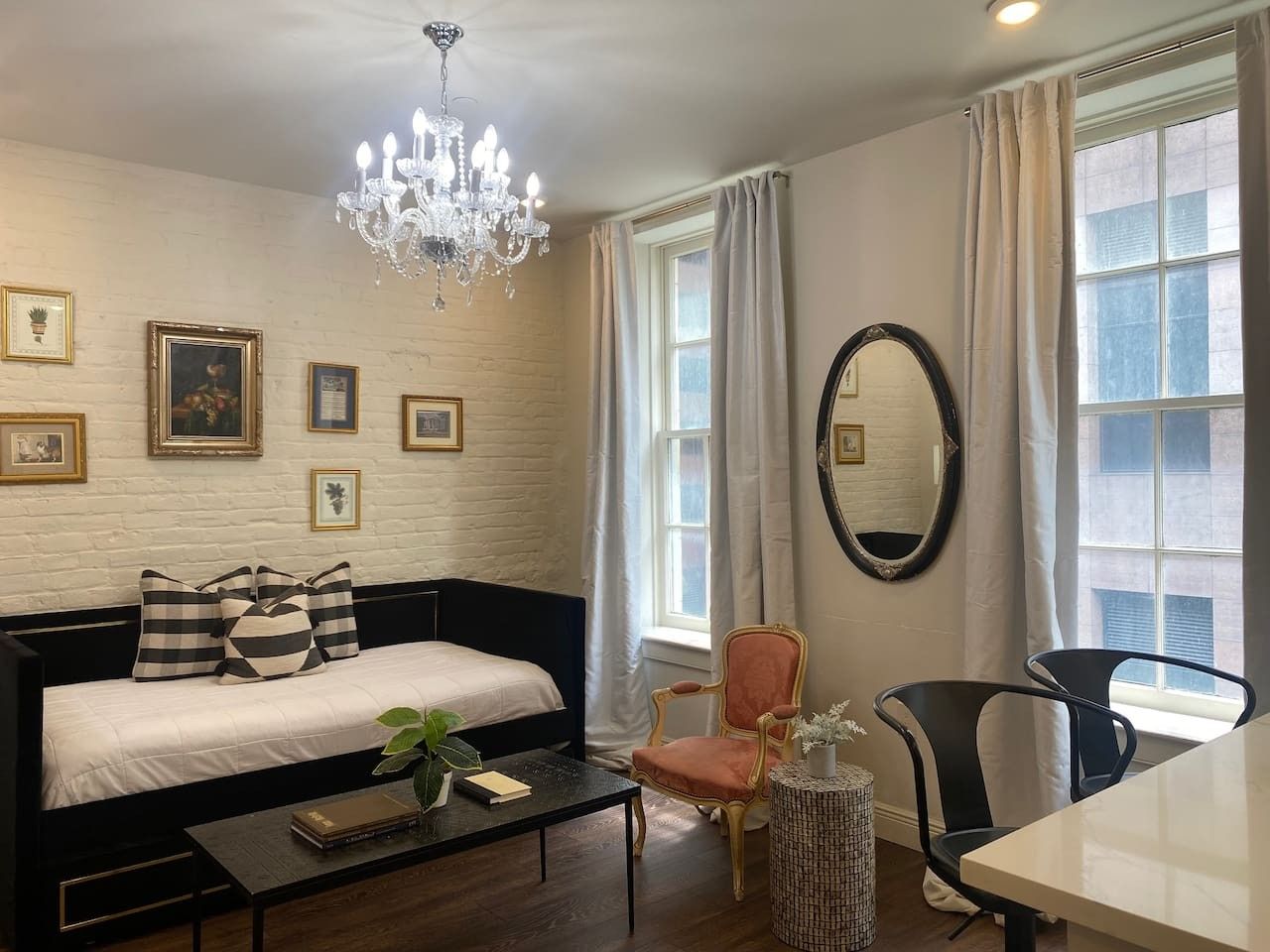 Habitación de hotel con cama, escritorio, silla, candelabro y un espejo grande.
