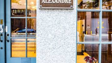 A building entrance with a sign reading 'THE ALEXANDRE' and a blue door.