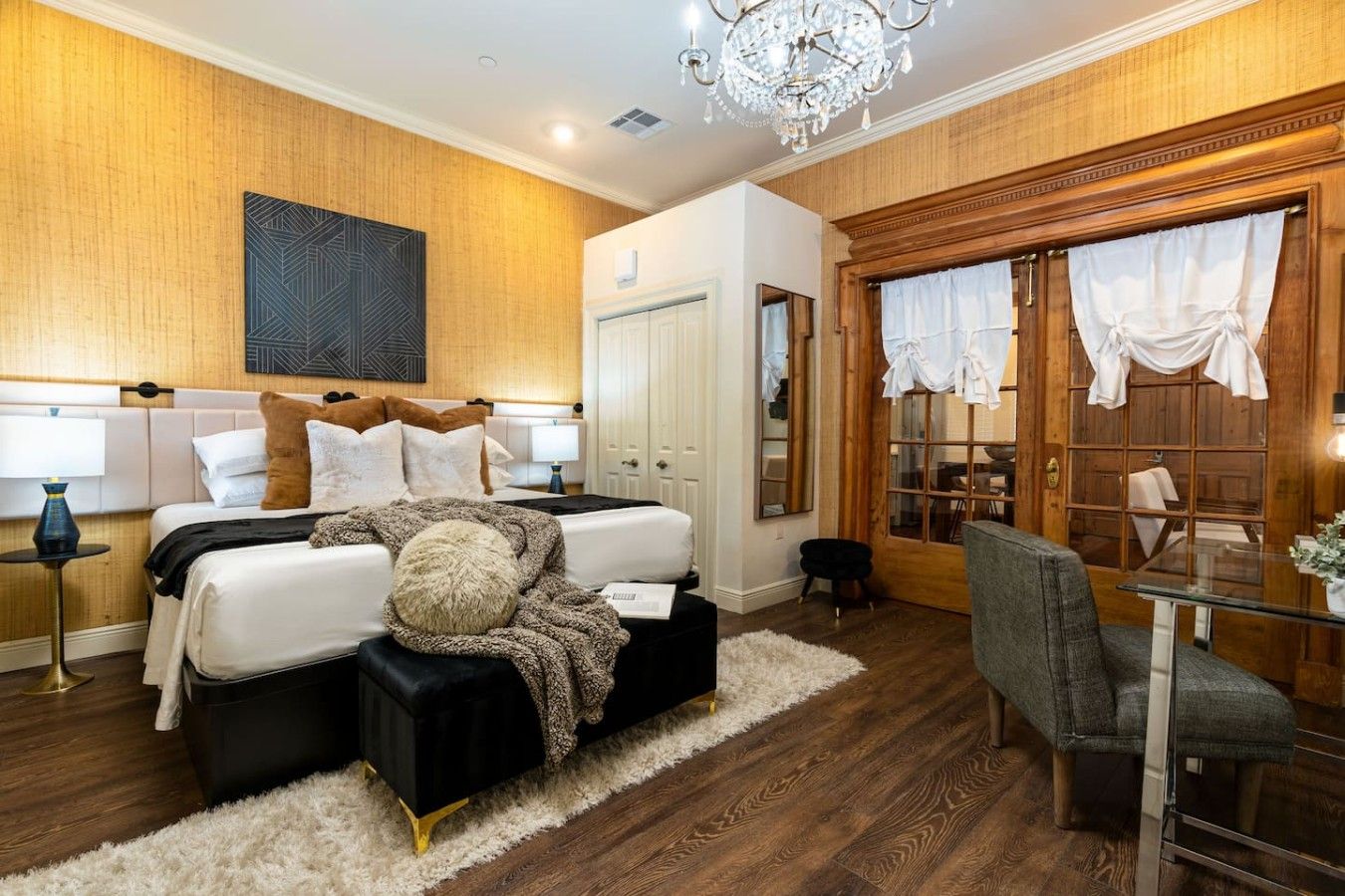 A modern bedroom with a large bed, a desk, and a chandelier.