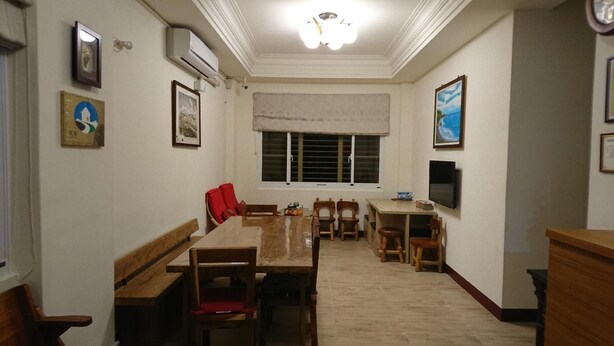 A dining area with a wooden table and chairs, a window with blinds, and a television on the wall. - Hohaiyan (Chenggong)