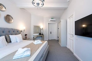 A hotel room with a bed, a flat-screen TV, a mirror, and a door leading to another room. - Highline Downtown Old Town Unirii Square (Bucharest)