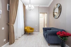 A room with a sofa, a chair, a mirror, and a vase with flowers. - Highline Downtown Old Town Unirii Square (Bucharest)