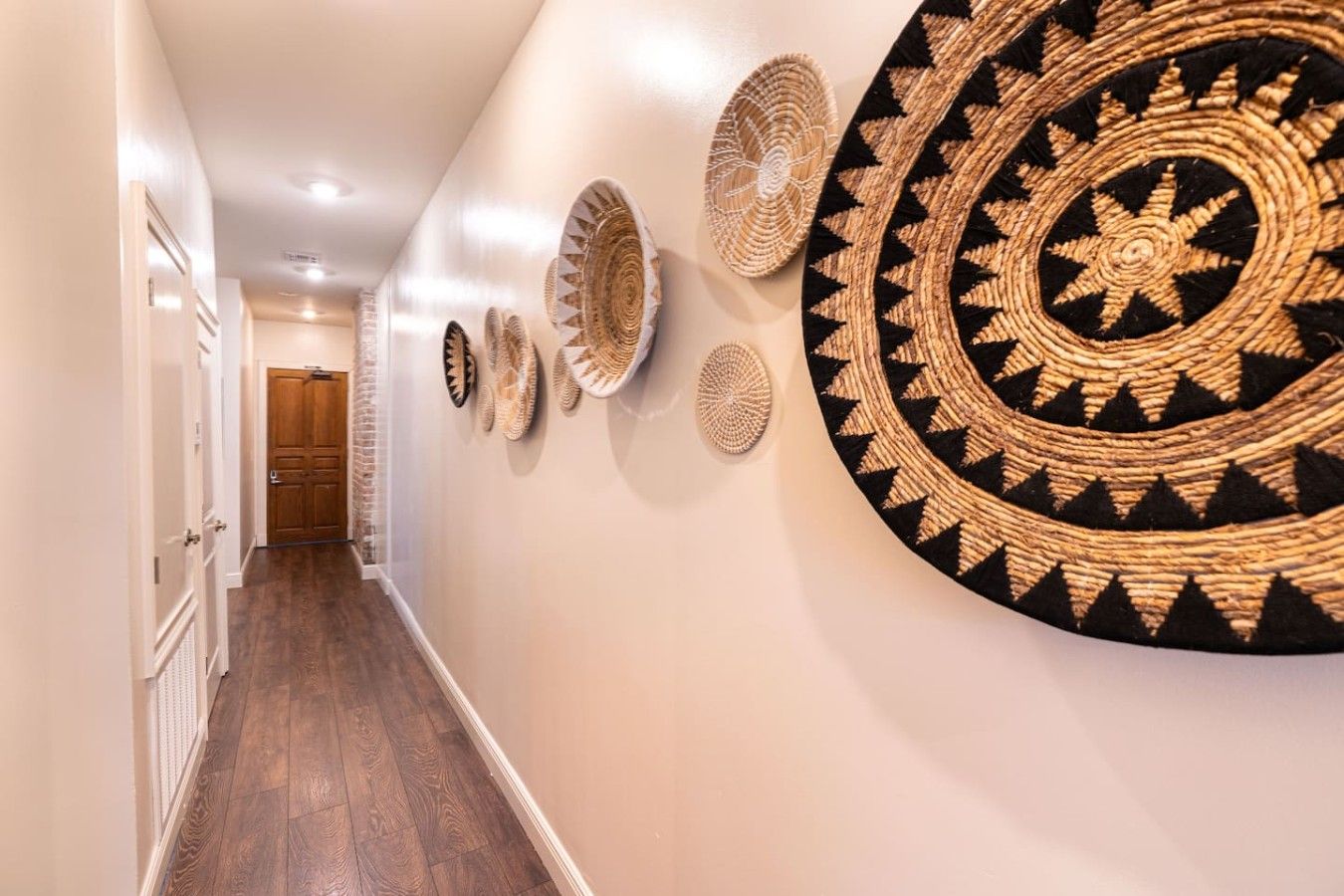 A hallway with a wooden floor, white walls, and a door at the end.