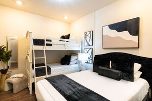 A bunk bed room with a single bed, a bedside table, a lamp, and a potted plant. - Bourbon Bliss | 2BD CBD Condo Near Canal St (New Orleans)