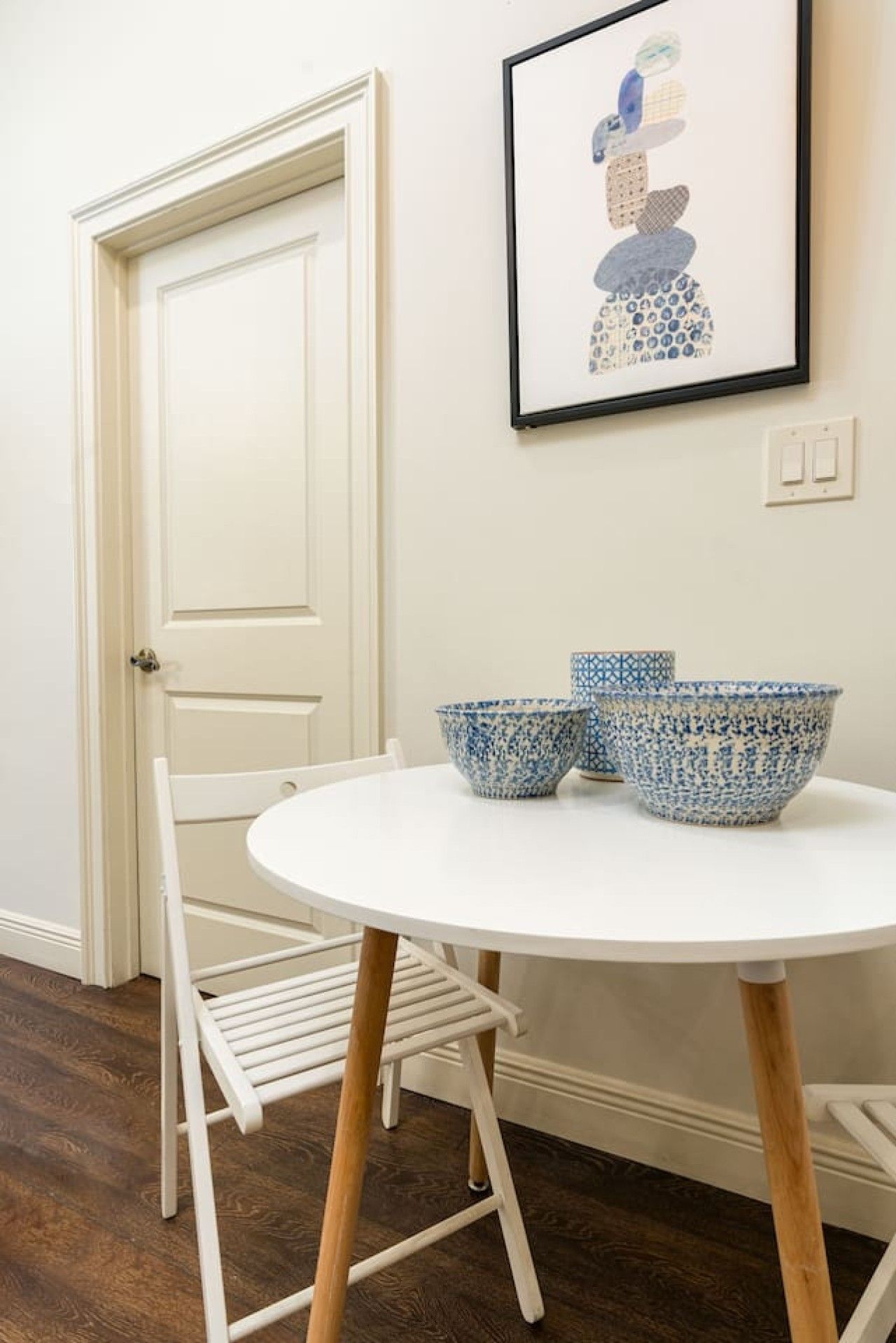 Une porte blanche, une chaise blanche, une table blanche et deux bols bleus à motifs.